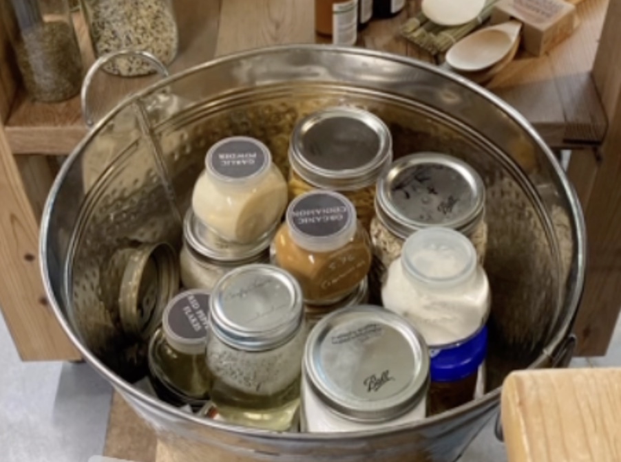 A customer's own glass jars, refilled at Exist Green and carried home in a reusable metal bucket